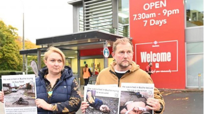Ukrainians Olha Viazenko and her husband Oleskii Ikonnikov hold posters outside Gardens New World supermarket yesterday, to protest the supermarket selling Russian beer. (Photo / Linda Robertson)