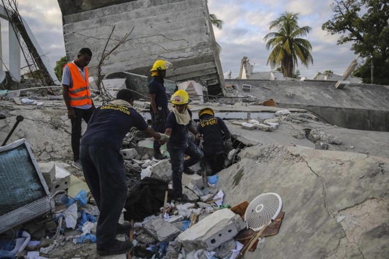 Firefighters search for survivors inside a collapsed building, after Saturday's 7.2 magnitude earthquake. (Photo / AP)