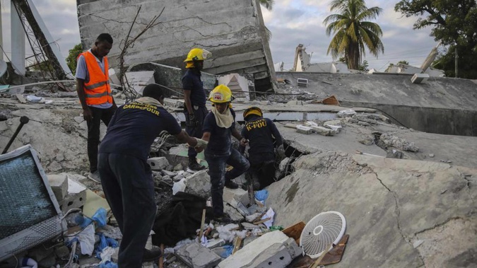 Firefighters search for survivors inside a collapsed building, after Saturday's 7.2 magnitude earthquake. (Photo / AP)