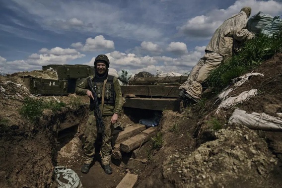 A Ukrainian soldier smiles standing in a trench on the frontline in the village of New York, Donetsk region, Ukraine, Monday, April 24, 2023. (AP Photo/Libkos)