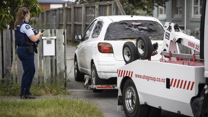 A white car, similar to one sought by police in relation to the stabbing, was towed away after police raided two properties in Aranui. Photo / George Heard.