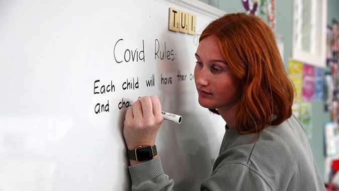 Kaipara Flats school teacher Allie Stucke writes Covid-19 instructions on the white board for the small number of students on April 28, 2020. (Photo / Getty Images)