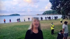 An anti-mandate protester pokes her tongue out as iwi perform a haka on Okahu Bay beach. (Photo / Supplied)