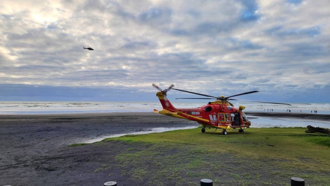 Westpac Rescue Helicopter and other emergency services on Karioitahi Beach searching for a missing swimmer.