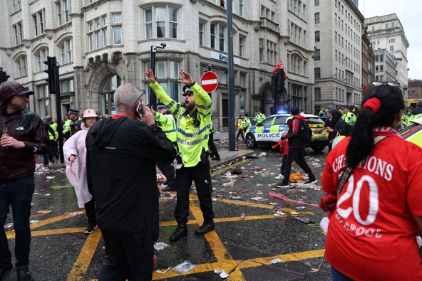 A police officer directs Liverpool fans at the entrance to Water St at the scene of an incident involving a car hitting pedestrians celebrating their team's Premier League title win. Photo / AFP