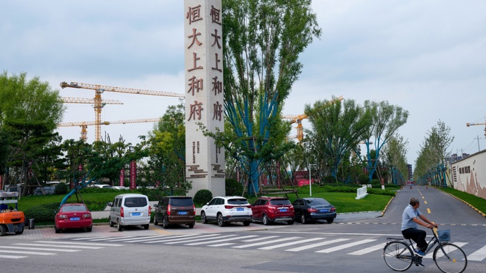 In this Sept. 15, 2021, file photo, a man bicycles past an Evergrande new housing development in Beijing. (Photo / AP)