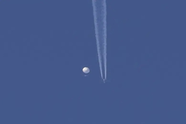  In this photo provided by Brian Branch, a large balloon drifts above the Kingstown, N.C. area, with an airplane and its contrail seen below it. The United States says it is a Chinese spy balloon moving east over America at an altitude of about 60,000 feet (18,600 meters), but China insists the balloon is just an errant civilian airshipused mainly for meteorological research that went off course due to winds and has only limited “self-steering” capabilities. (Brian Branch via AP)