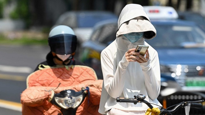 A woman wearing sun protective clothing commutes on a bicycle amid hot weather in Shanghai on Monday. Stringer/AFP/Getty Images