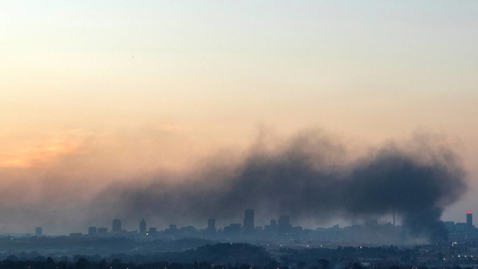 Smoke covers the Johannesburg skyline as people protests in downtown area, in Johannesburg, South Africa, Sunday, July 11, 2021. (Photo / AP)