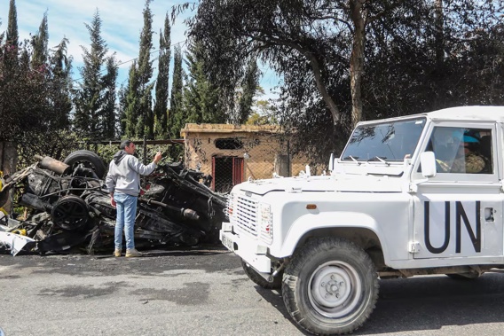 A UN peacekeeper vehicle passes next to a destroyed car in the southern outskirts of Tyre, Lebanon. Photo / AP
