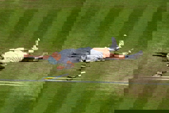 Australia's Nick Kyrgios lies on the ground after defeating Chile's Cristian Garin during a men's singles quarterfinal a Wimbledon. Photo / AP