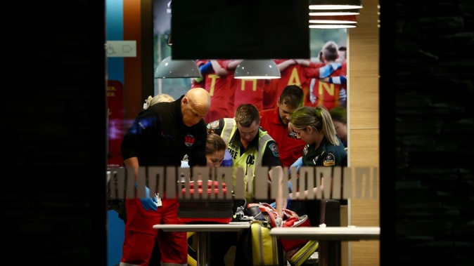 Emergency personnel treat a badly injured taxi driver at a McDonald's restaurant in Christchurch where he reportedly sought help after a stabbing incident elsewhere. Photo / George Heard