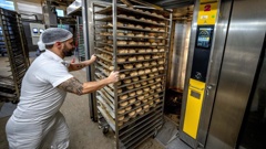  An employee pushes bread rolls into one of the gas heated ovens in the producing facility in Cafe Ernst in Neu Isenburg, Germany, Monday, Sept. 19, 2022. Andreas Schmitt, head of the local bakers' guild, said some small bakeries are contemplating giving up due to the energy crisis. (AP Photo/Michael Probst)