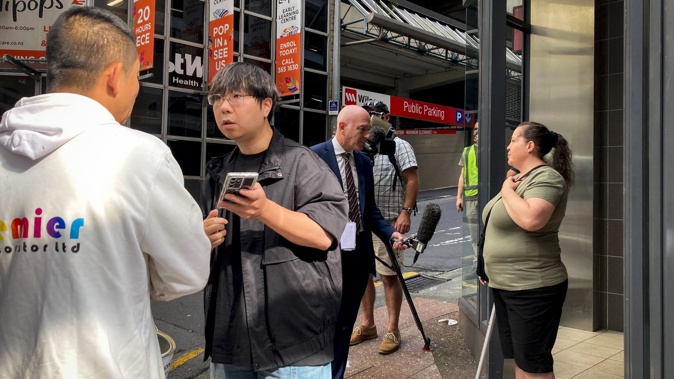 Residents outside the City Garden Apartments on Albert Street central Auckland under an Auckland Council Dangerous Building Notice