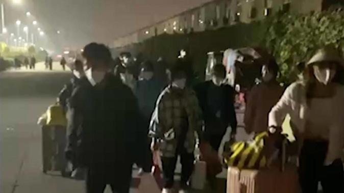 People with suitcases and bags are seen leaving a Foxconn compound in Zhengzhou in central China's Henan Province. Photo / Hangpai Xingyang
