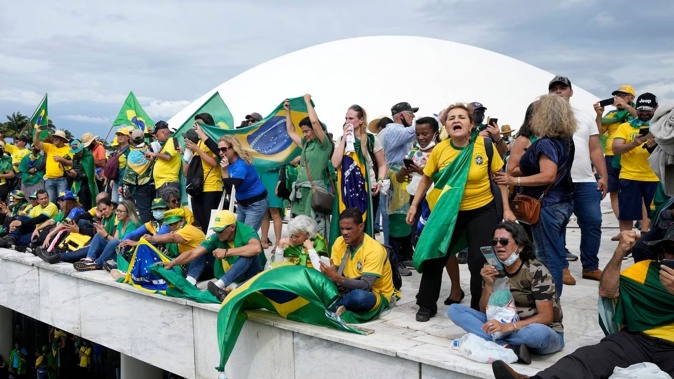 Protesters, supporters of Brazil's former President Jair Bolsonaro, stand on the roof of the National Congress building after they stormed it, in Brasilia, Brazil. Photo / AP