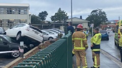 Emergency services attended a crash on Shore St after a vehicle crashed through the Bayfield High School fence and landed on two parked cars. Photo / Craig Baxter