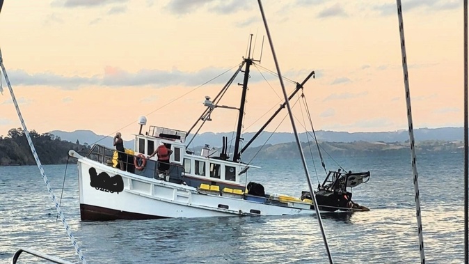 The trawler with the fishermen still aboard, minutes before the vessel was completely submerged. Photo / Facebook