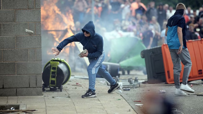 Riot police clash with anti-migration protesters outside of a Holiday Inn Express, which is being used as an asylum hotel. Photo / Getty Images