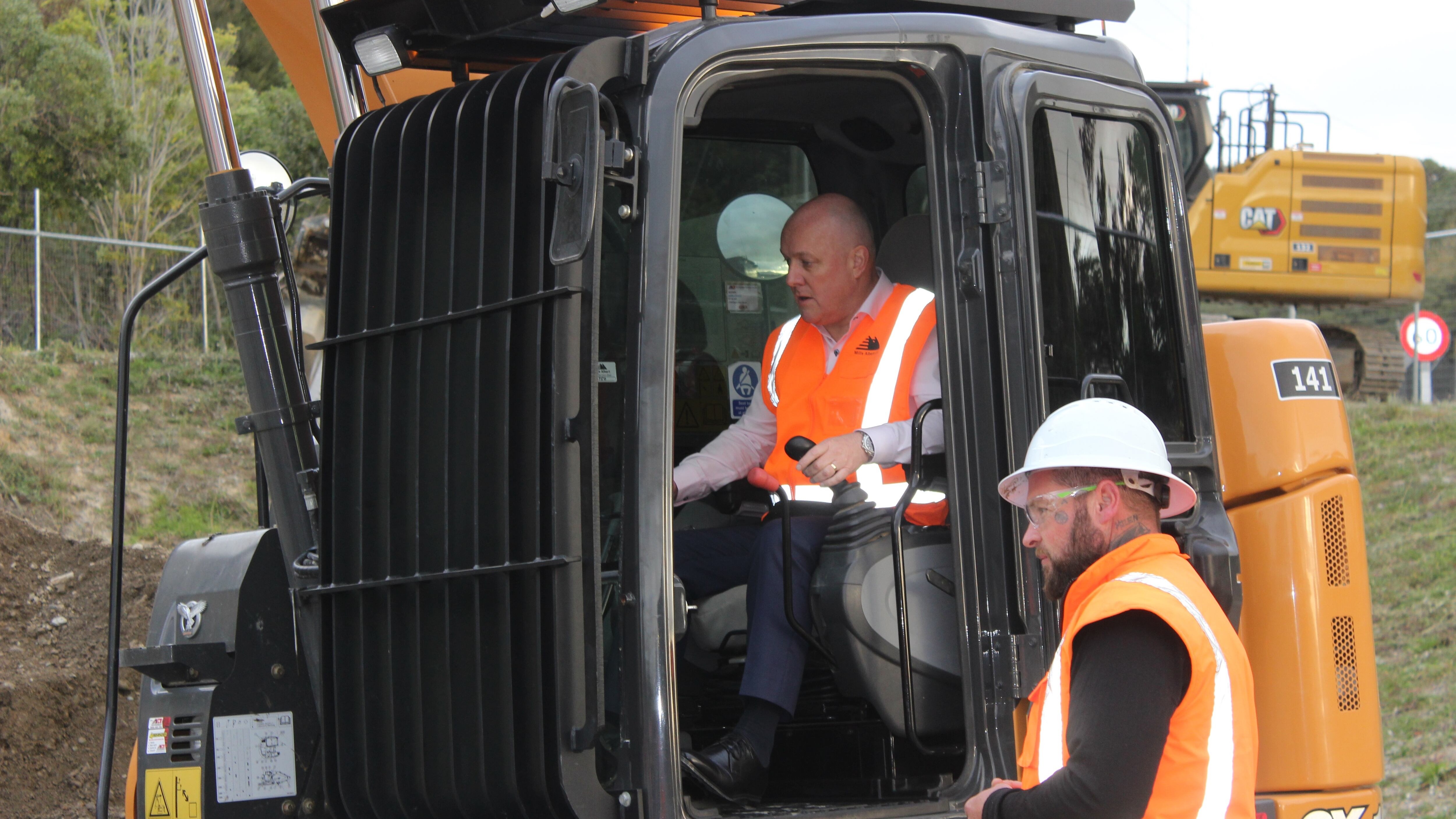 Prime Minister Christopher Luxon, guided by Stace Keen, controls a digger at Central Districts Field Days in Feilding. Photo / David Haxton