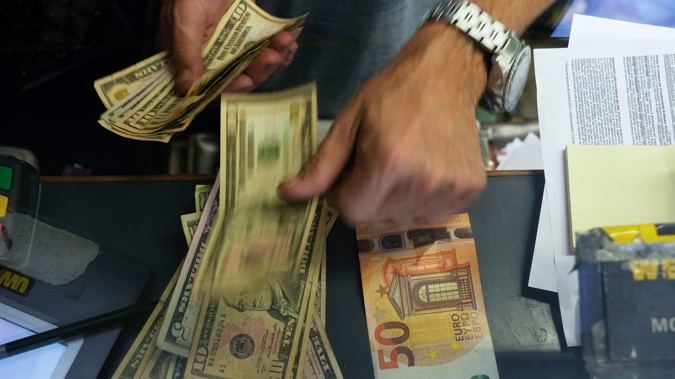 A cashier changes a 50 Euro banknote with US dollars at an exchange counter in Rome. Photo / AP