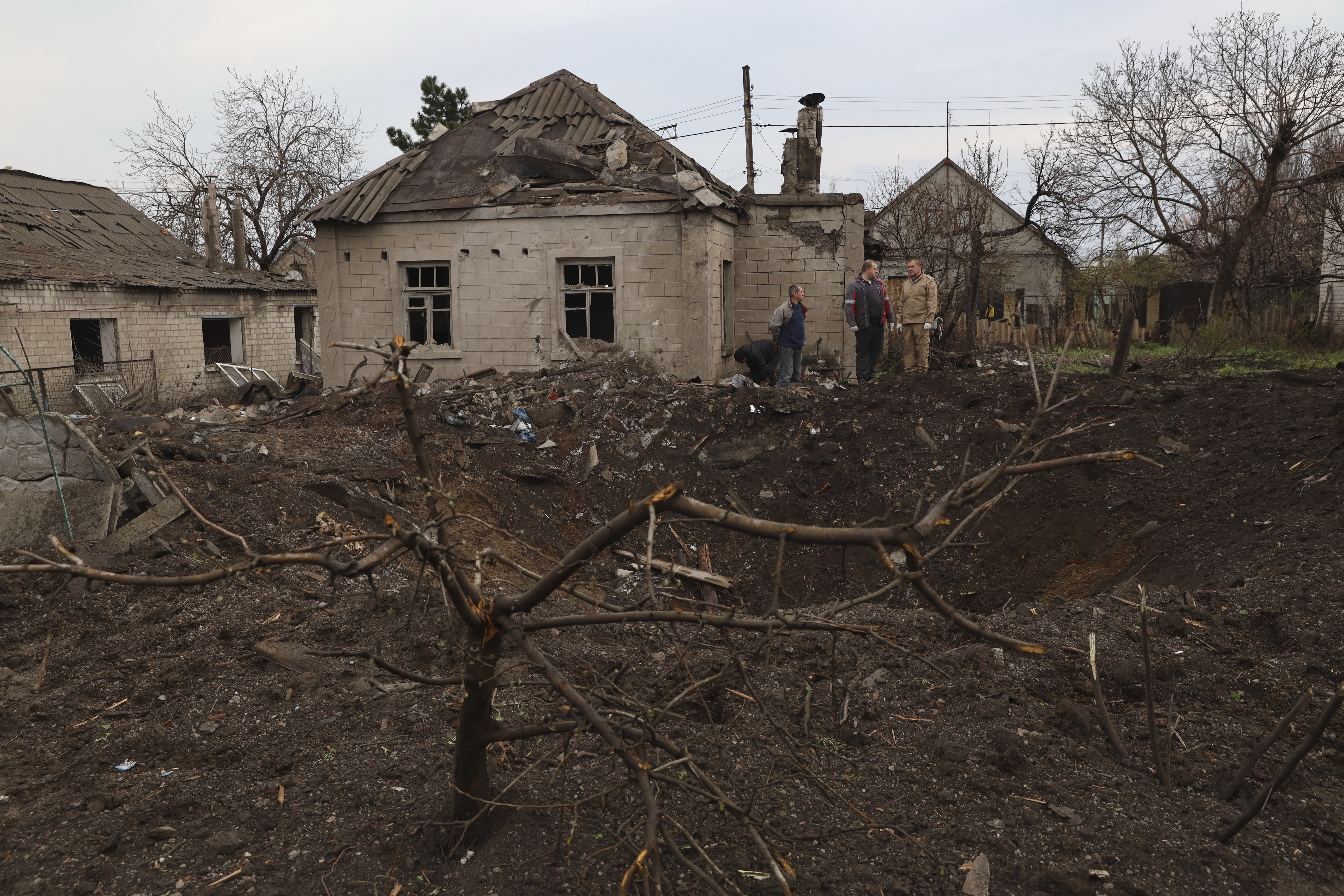 Local residents stand near a crater left by a Russian missile in Zaporizhzhia , Ukraine, Sunday, April 9, 2023. An 11-year old girl and her father were killed in the rocket attack in Zaporizhzhia. Photo / AP