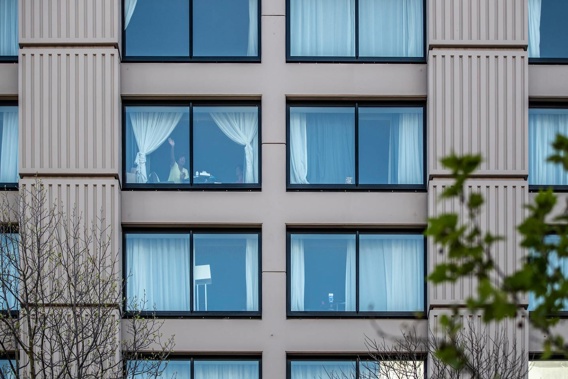 A recent arrival waves from a room at the Grand Millennium MIQ hotel in Auckland. (Photo / Michael Craig)