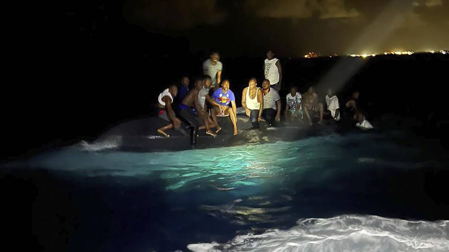 Survivors sit on a capsized boat as they are about to be rescued near New Providence in the Bahamas. Photo / AP