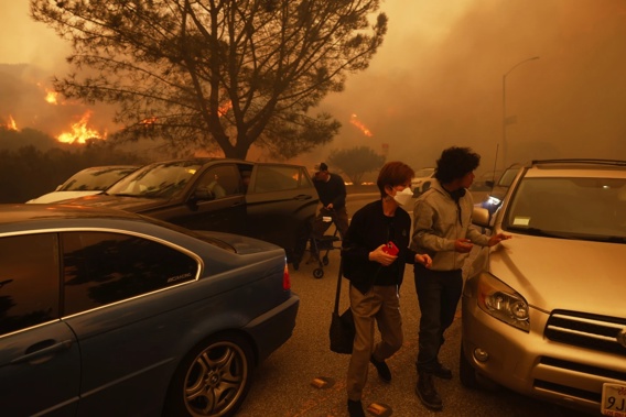 People flee from the advancing Palisades Fire, by car and on foot, in the Pacific Palisades neighbourhood of Los Angeles. Photo / AP / Etienne Laurent