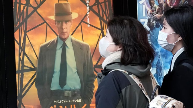People walk by a poster to promote the movie Oppenheimer on March 29, 2024, in Tokyo. Photo / AP