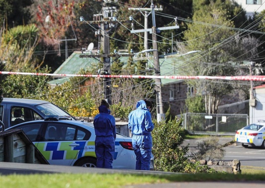 Forensic staff inspect the area around the patrol car parked in the driveway of an O'Donoghue St flat where a man - who was shot by police - had been living. Photo / Mike Scott