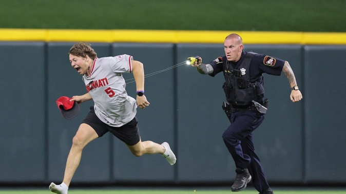 An unidentified fan is tased by a police officer as he runs on the field before the ninth inning of the Cincinnati Reds against Cleveland Guardians. Photo / Getty Images