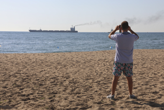 A man takes a picture as the Glory bulk carrier makes its way from the port in Odesa, Ukraine. Photo / AP