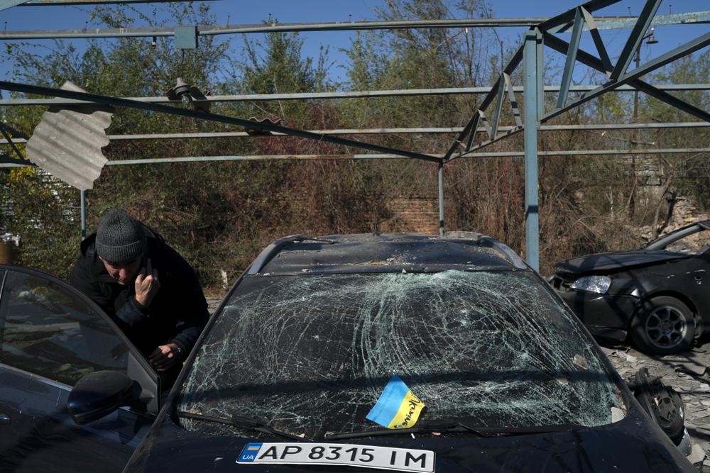 Dmytro Pocishchuk checks his car, which was damaged after a Russian attack in Zaporizhzhia, Ukraine, Saturday, Oct. 15, 2022. (AP Photo/Leo Correa)