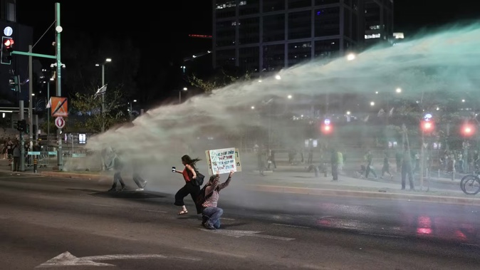 Police use a water cannon to disperse demonstrators blocking a road during a protest against Israeli Prime Minister Benjamin Netanyahu's government, and calling for the release of hostages held in the Gaza Strip by the Hamas militant group, in Tel Aviv. Photo / AP