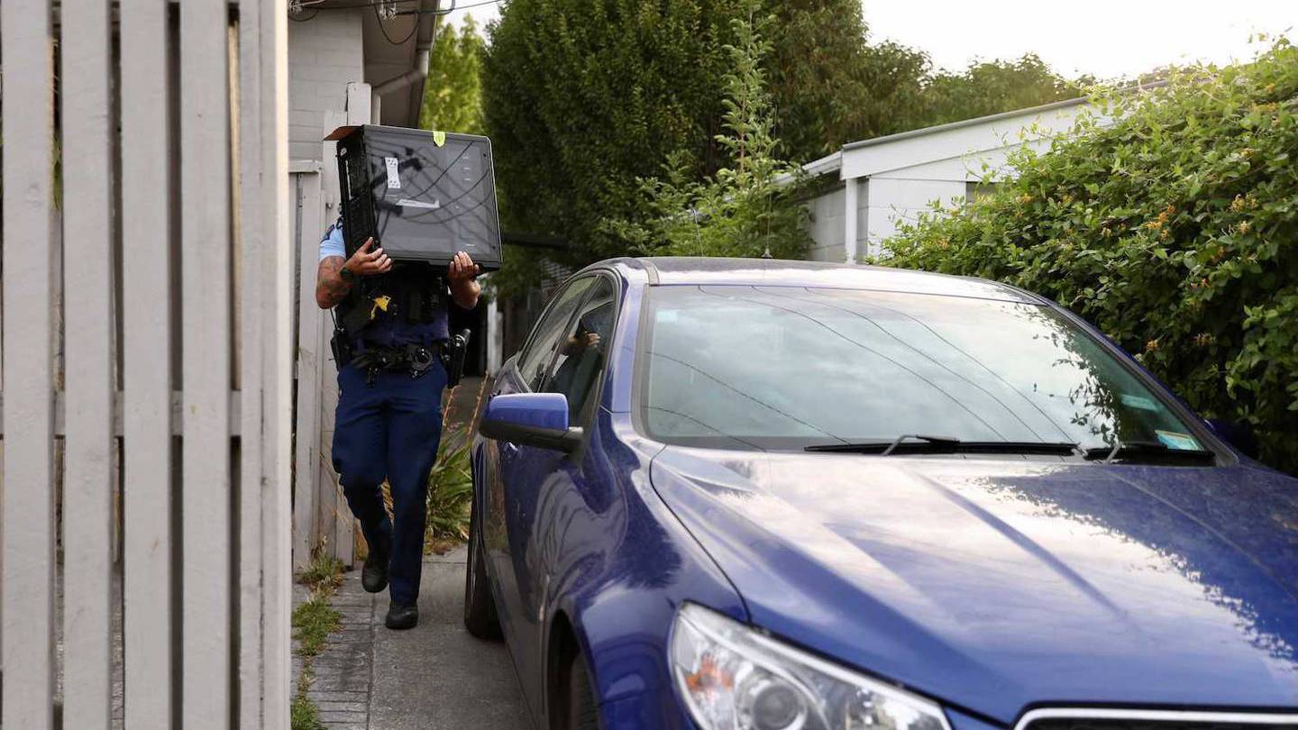 Police take computer equipment out of the house in Christchurch. Photo / George Heard