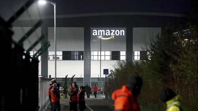 Members of Amazon security keep an eye on members of the GMB union picketing outside the Amazon fulfilment centre in Coventry, England. Photo / AP