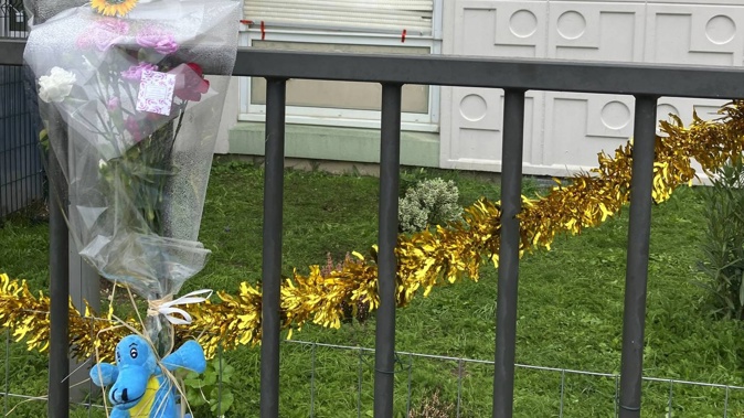 Flowers lay at the building gate where four children and their mother were found killed. Photo / AP