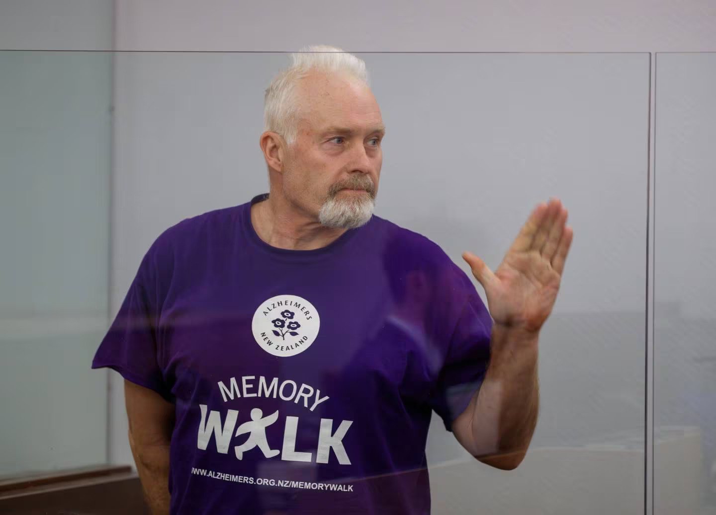 Barry Young waving to supporters as he enters the dock for his bail hearing in the Wellington District Court. Photo / Mark Mitchell