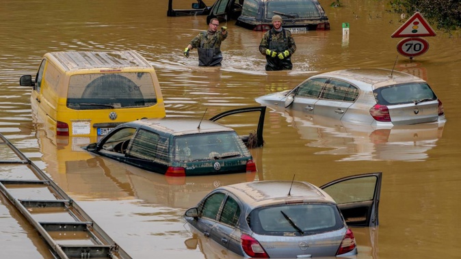 Helpers check for victims in flooded cars on a road in Erftstadt, Germany yesterday. Due to strong rainfall, the small Erft river went over its banks, causing massive damage. Photo / AP