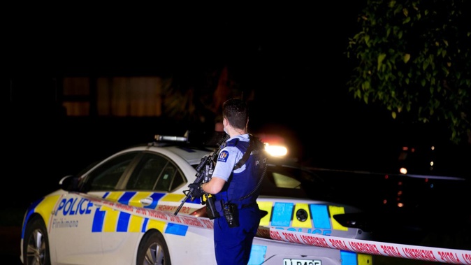 An armed police officer at the scene of a gang-related shooting incident in Massey, Auckland, early Wednesday. Photo / Hayden Woodward