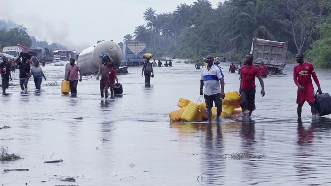 FILE- People wade through flooded roads in Bayelsa, Nigeria, Oct. 20, 2022. Climate change is to blame for the deadliest yet heavy rains and flooding that swamped Nigeria, Niger, Chad, and the neighboring Sahel region between the months of June and October leaving more than 800 people dead. (AP Photo/Reed Joshua, File)