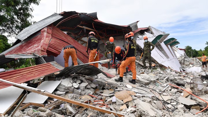 Rescuers search for three people who were reported missing under the rubble of a collapsed building in Bogo City. Photo / Ted Aljibe, AFP