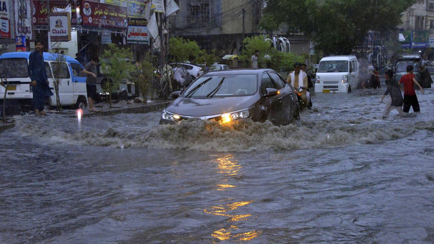 Motorcyclists and cars drive through a flooded road caused by heavy monsoon rainfall in Hyderabad, Pakistan. Photo / AP