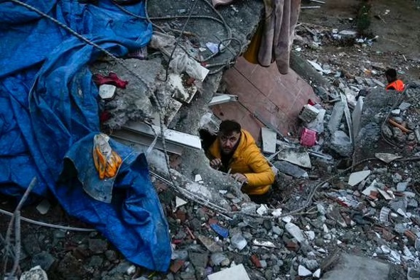 A man searches for people in a destroyed building in Adana, Turkey, after the quake. Photo / AP