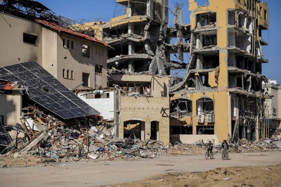Palestinians ride bicycles by destroyed buildings in Gaza City. Photo / AP