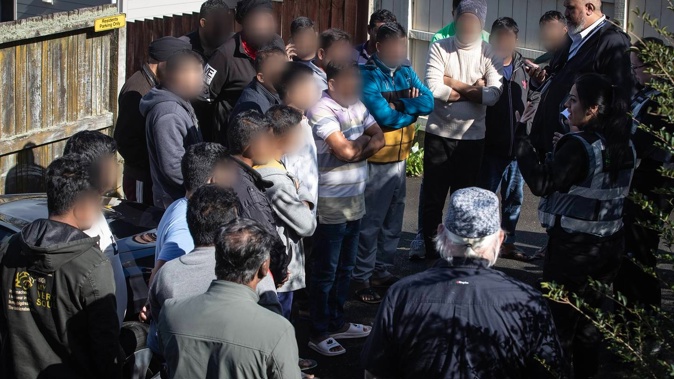Officials from Immigration NZ, Auckland Council and Fire and Emergency NZ speaking to occupants found in an overcrowded Lynfield house. Photo / Jason Oxenham