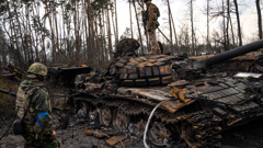 A Ukrainian soldier stands on top of a destroyed Russian tank on the outskirts of Kyiv on March 31. (Photo / AP)