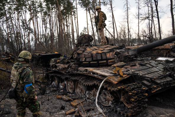 A Ukrainian soldier stands on top of a destroyed Russian tank on the outskirts of Kyiv on March 31. (Photo / AP)
