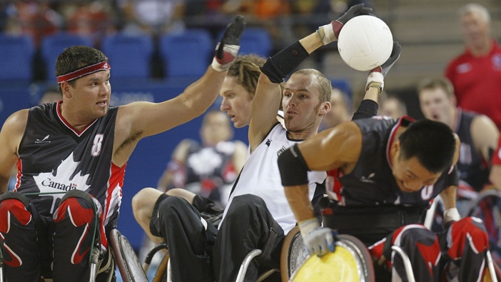 Gerry Tinker of New Zealand (C) fends off Michael Whitehead (L) and Ian Chan (R) of Canada during final Wheelchair Rugby mach between New Zealand and Canada at the Athens 2004 Paralympic Games, on September 25, 2004 in Athens, Greece. (Photo by Milos Bicanski/Getty Images)